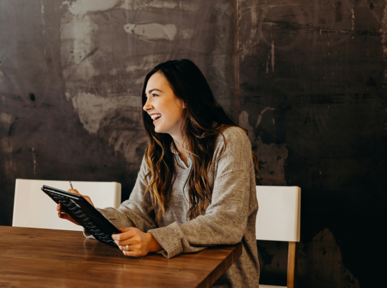 brooke-cagle-JBwcenOuRCg-unsplash (1) Smiling professional woman holding a notebook, symbolizing confident legal support at Ceiba Law